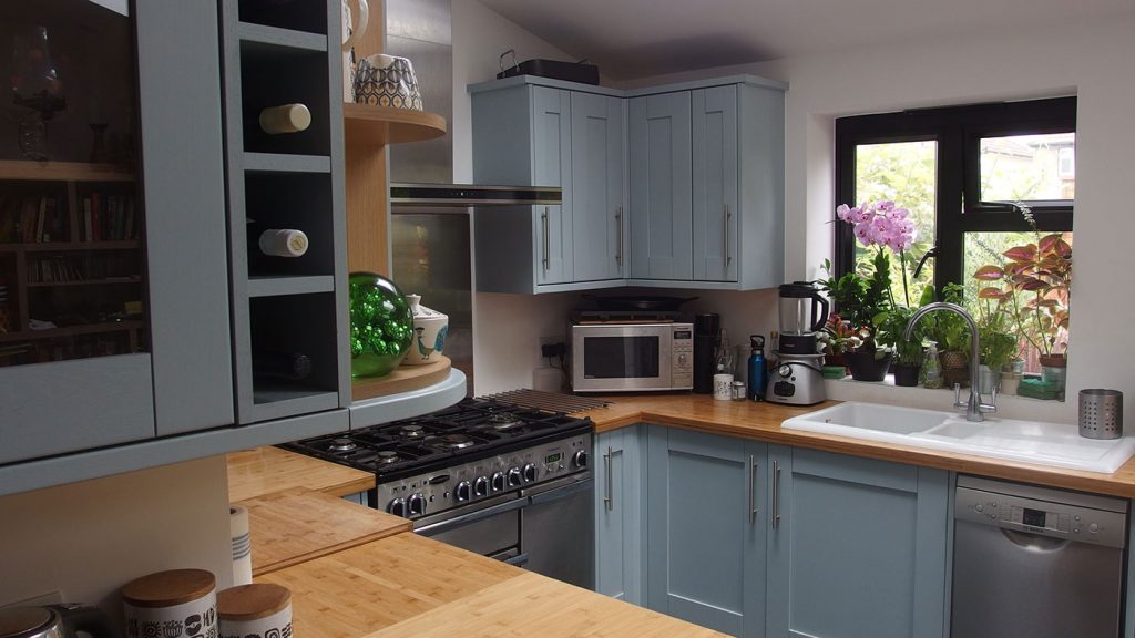 Kitchen with bamboo worktop and blue cupboards.